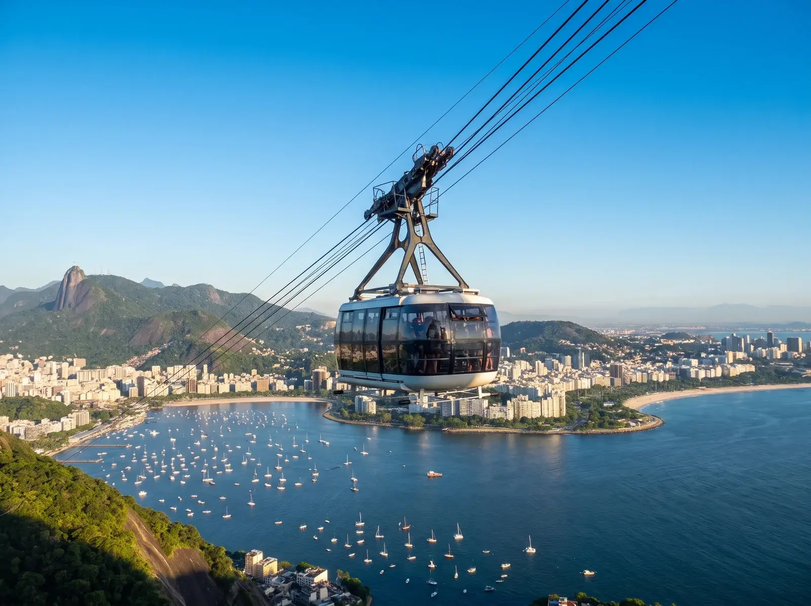 Şekerleme Dağı teleferiğinin kabini, teknelerle dolu koyun, kıyı binalarının ve yeşil tepelerin üzerinde asılı duruyor.