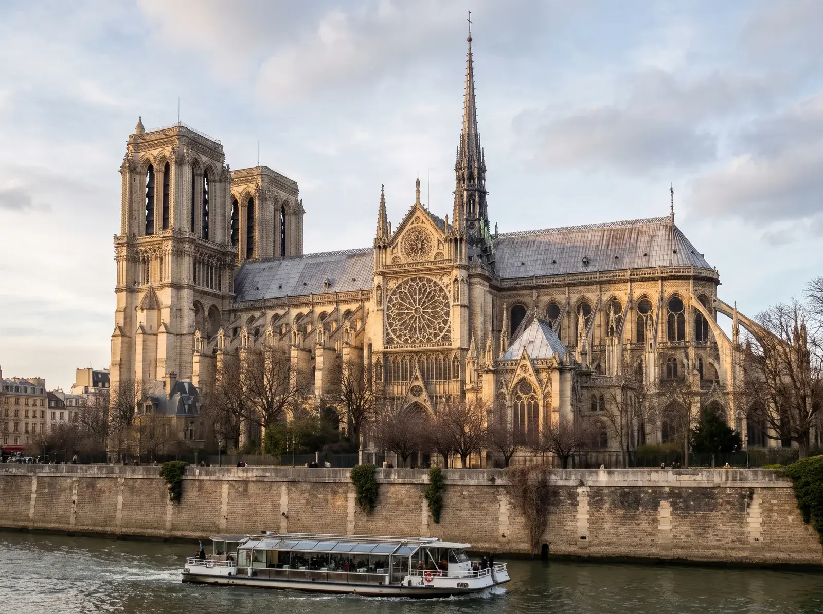 Seine'deki gezi teknesinin arkasında Notre-Dame'ın uçan payandaları ve yenilenen sivri kulesi.